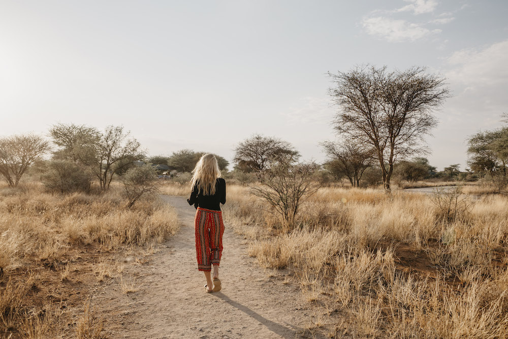 Africa, Namibia, blonde woman walking on way in grassland