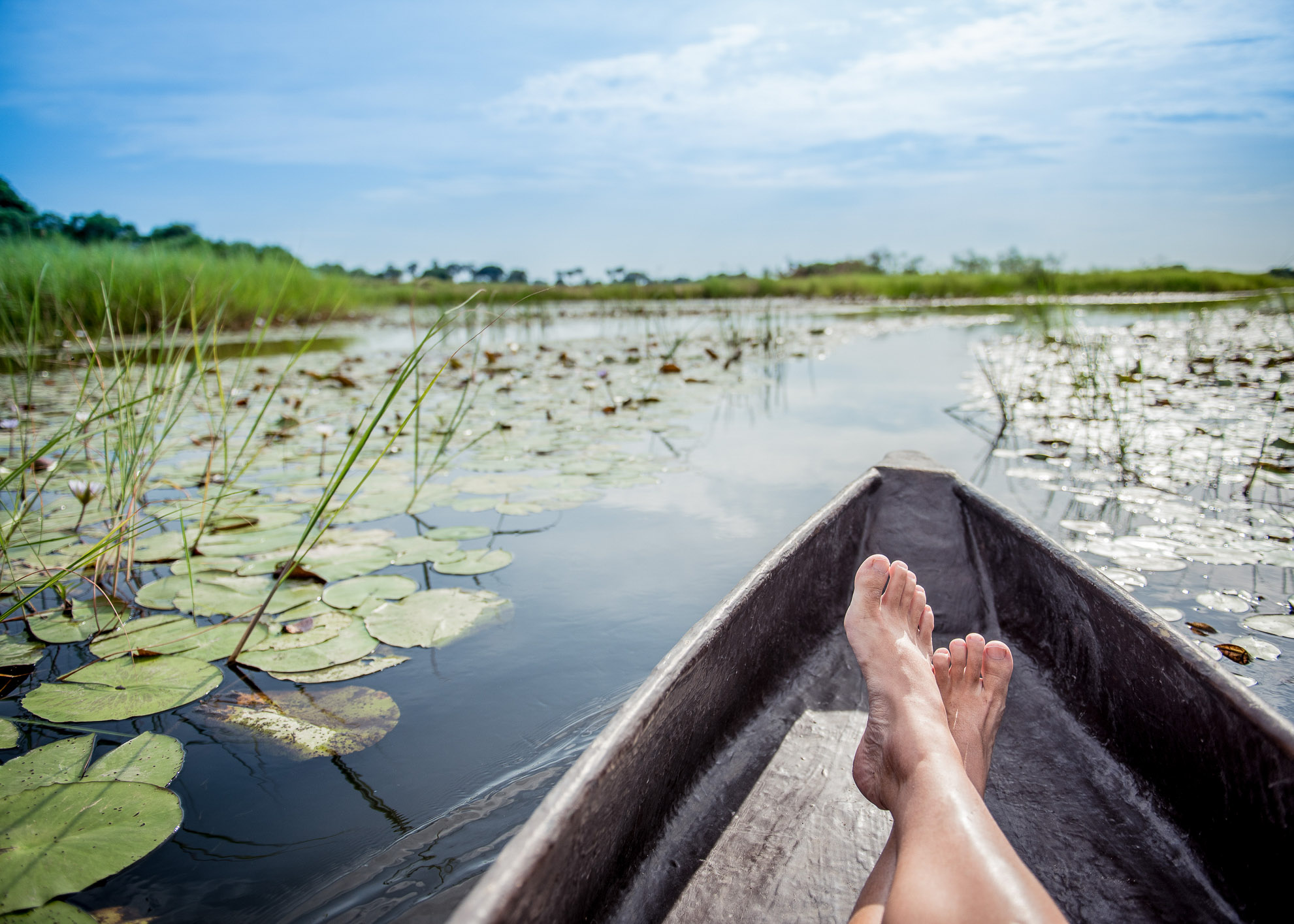 Tourist sitting with legs crossed in Mokoro in the okavango delta, botswana, africa.