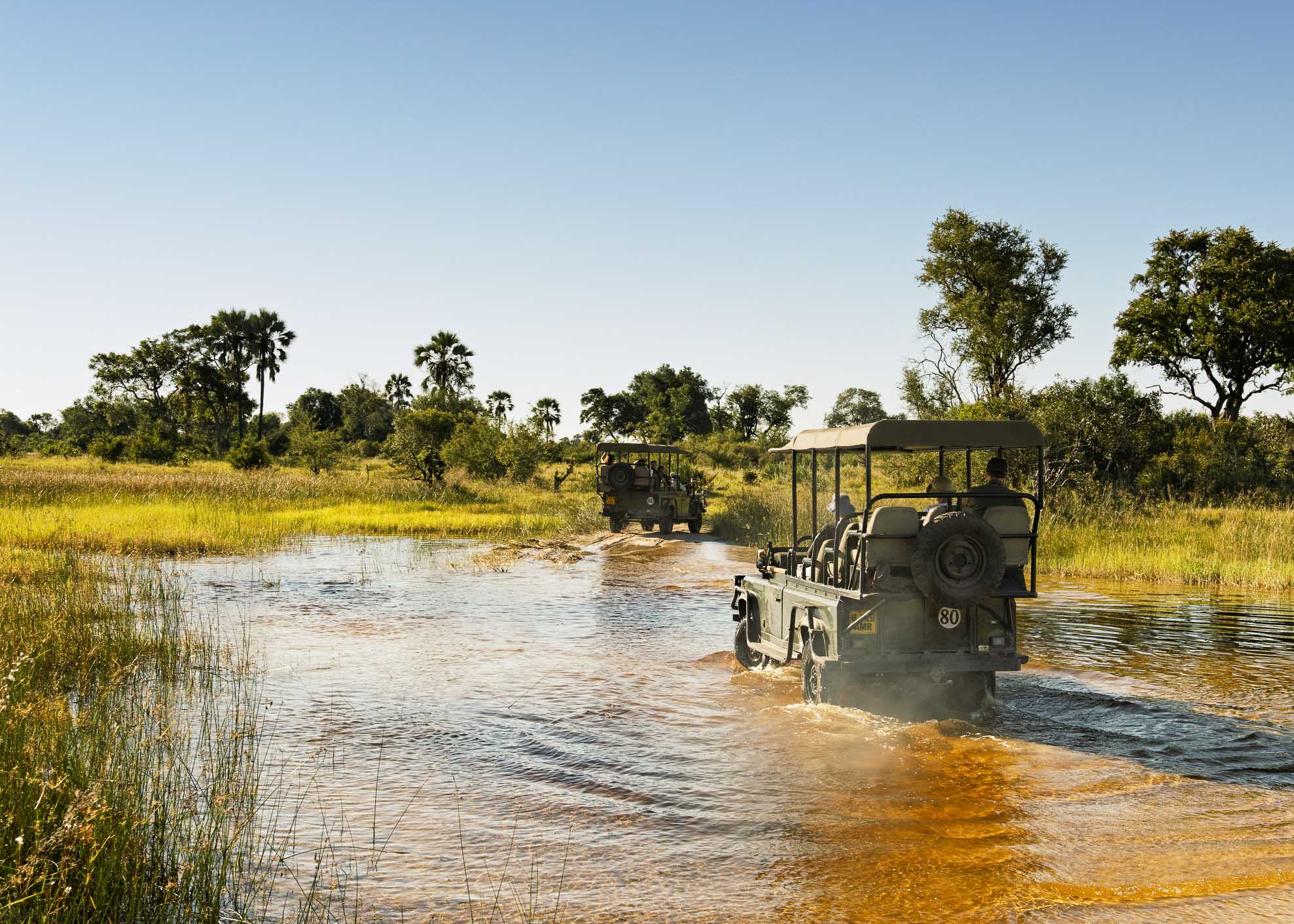 Chitabe Concession ,Botswana - April 2, 2012: Safari vehicles with tourists driving through the water at the end of the rainy season during a game drive in the Okavango Delta.